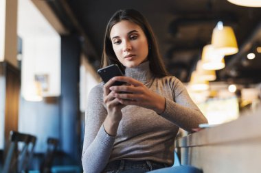 Çekici iş kadını dizüstü bilgisayarın önünde oturuyor ve cep telefonuyla konuşuyor, telefonda görüşüyor.. 