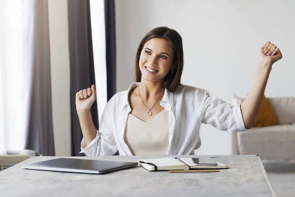 Beautiful brunette woman has completed business project, is happy. Girl sits at desk in home office. Distance work — Stock Photo, Image