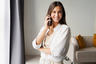 Akıllı telefondan konuşan iş kadını. Güzel kız iş için cep telefonu kullanıyor, müşterileri arıyor, mesajlar gönderiyor.