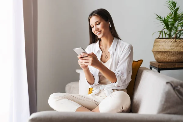 Feminino relaxante em casa, usando smartphone para mensagens de texto, compartilhar fotos, comunicar com amigos, verificar e-mail — Fotografia de Stock