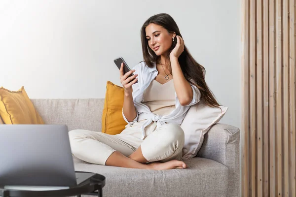 Atrakcyjna bizneswoman siedzi przy stole przed laptopem i rozmawia przez telefon komórkowy, negocjuje przez telefon. — Zdjęcie stockowe