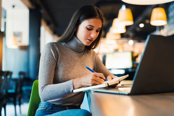 Enseñanza a distancia. Hermosa mujer sonriente en camisa blanca trabaja en frente de la computadora portátil. Un estudiante prepara seminario — Foto de Stock