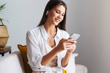 Kadın evde dinleniyor, akıllı telefonu mesajlarda kullanıyor, fotoğrafları paylaşıyor, arkadaşlarıyla iletişim kuruyor.