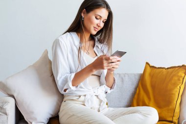 Kadın evde dinleniyor, akıllı telefonu mesajlarda kullanıyor, fotoğrafları paylaşıyor, arkadaşlarıyla iletişim kuruyor.