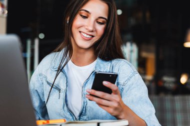 Çekici iş kadını dizüstü bilgisayarın önünde oturuyor ve cep telefonuyla konuşuyor, telefonda görüşüyor.. 