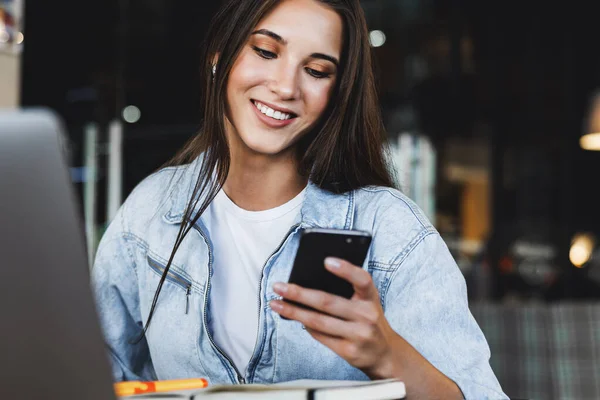 Çekici iş kadını dizüstü bilgisayarın önünde oturuyor ve cep telefonuyla konuşuyor, telefonda görüşüyor.. 