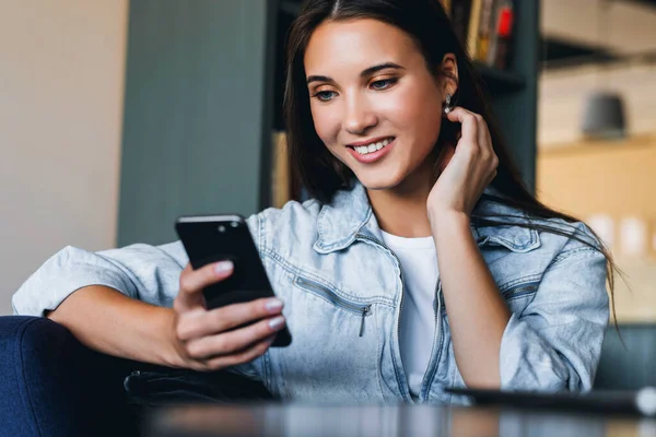 Attraente donna d'affari si siede a tavola davanti al computer portatile e parla al telefono cellulare, negozia al telefono. — Foto Stock