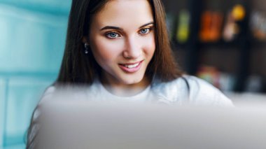 İş kadını dizüstü bilgisayarın önünde oturuyor, online eğitim alıyor, ev ofisinden çalışıyor. Yakın plan portre.