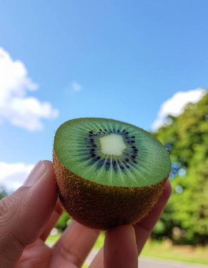 Taze Dilimlenmiş Kivi Meyvesinin Kapanışı Mavi Gökyüzü Arkaplanına Karşı El Tarafından Tutulan