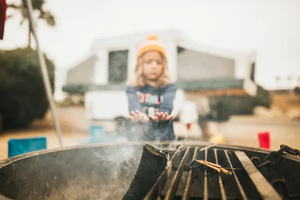 Dívka oteplování ruce u grilu — Stock fotografie