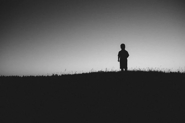 Silhouette del ragazzo in piedi sul campo — Foto Stock