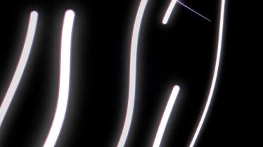 Parlayan neon ışıkları, koyu arkaplanda dans ederek beyaz ve mor renklerle soyut desenler oluşturur. Parlak çizgiler dinamik görsel efekt yaratır, enerji ve hareket taşınır..