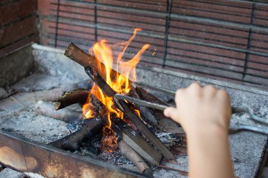 Başlangıç ateş kömür ızgara için. Uzun saplı maşa ayar yangın Closeup kolla. Parlak alevler ve yanan odun. Izgara bul. Hazırlık barbekü için ateş.