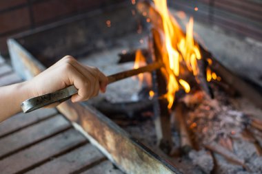 Başlangıç ateş kömür ızgara için. Uzun saplı maşa ayar yangın Closeup kolla. Parlak alevler ve yanan odun. Izgara bul. Hazırlık barbekü için ateş.