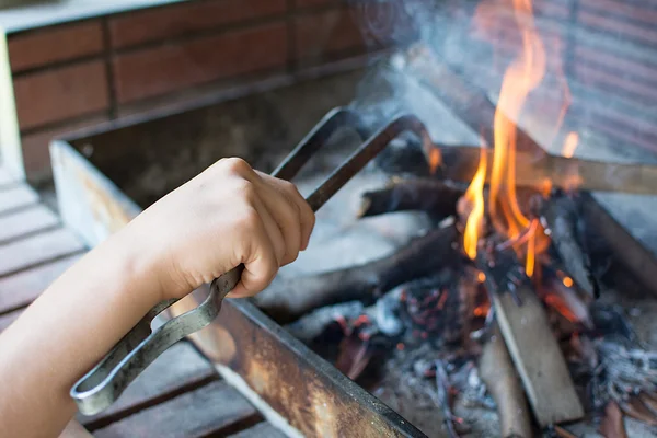 Starting Fire for Charcoal Grill. Arm With Long-Handled Tongs Setting Fire Closeup. Bright Flames and Burning Wood. Get Your Grill On. Fire Preparation for Barbecue. — Stock Photo, Image