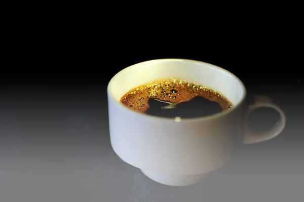 Una taza de café en una mesa de cristal. Taza de café blanco de cerca con fondo oscuro y luz dramática. Enfoque selectivo, espacio de copia y profundidad de campo poco profunda . — Foto de Stock