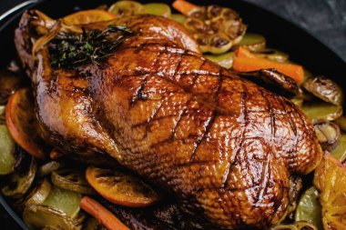 Whole Duck Roasted with Oranges, Carrots and Potatoes on Rustic Dark Stone Background