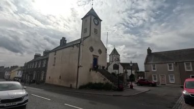 Traditional stone-built houses and commercial buildings lining the main street in Lauder town center Scottish Borders featuring pitched slate roofs, timber-framed windows, colorful doors, and views to town hall clock tower
