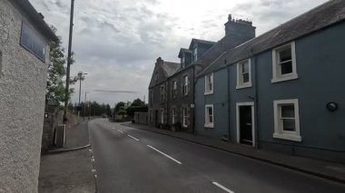 Traditional stone-built houses and commercial buildings lining the main street in Lauder town center Scottish Borders featuring pitched slate roofs, timber-framed windows, colorful doors, and views to town hall clock tower
