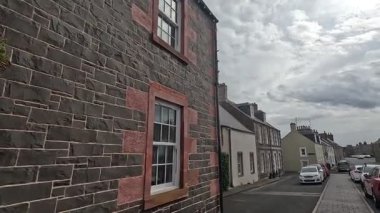Traditional stone-built houses and commercial buildings lining the main street in Lauder town center Scottish Borders featuring pitched slate roofs, timber-framed windows, colorful doors, and views to town hall clock tower