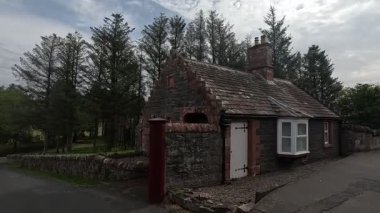 Traditional stone-built houses and commercial buildings lining the main street in Lauder town center Scottish Borders featuring pitched slate roofs, timber-framed windows, colorful doors, and views to town hall clock tower