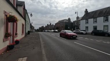 Traditional stone-built houses and commercial buildings lining the main street in Lauder town center Scottish Borders featuring pitched slate roofs, timber-framed windows, colorful doors, and views to town hall clock tower