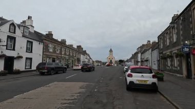 Traditional stone-built houses and commercial buildings lining the main street in Lauder town center Scottish Borders featuring pitched slate roofs, timber-framed windows, colorful doors, and views to town hall clock tower