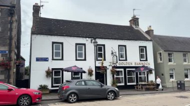 Traditional stone-built houses and commercial buildings lining the main street in Lauder town center Scottish Borders featuring pitched slate roofs, timber-framed windows, colorful doors, and views to town hall clock tower