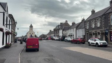 Traditional stone-built houses and commercial buildings lining the main street in Lauder town center Scottish Borders featuring pitched slate roofs, timber-framed windows, colorful doors, and views to town hall clock tower