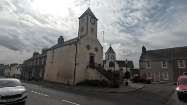 Traditional stone-built houses and commercial buildings lining the main street in Lauder town center Scottish Borders featuring pitched slate roofs, timber-framed windows, colorful doors, and views to town hall clock tower