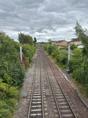 Edinburgh İskoçya 'da şehir demiryollarına bakan perspektifte uyuyanların üzerinde çift çelik raylar, ezilmiş taş safraları, elektrik hatları yan yana eskrim ve bulutlu gökyüzü altında binaların ve yeşil alanların arka planları yer alıyor..