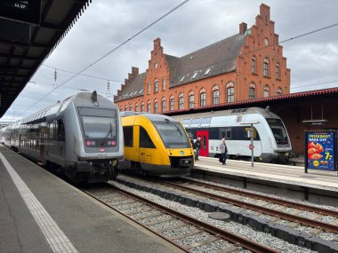View of multiple passenger trains in Helsingor railway station Denmark, including platforms, tracks, and signage for Kystbanen line connections to Copenhagen and regional destinations.