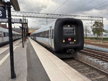 View of multiple passenger trains in Helsingor railway station Denmark, including platforms, tracks, and signage for Kystbanen line connections to Copenhagen and regional destinations.