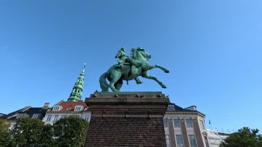 Urban scene in Copenhagen city centre captures Nyhavn canal lined with 17th century buildings, bicycles parked along the waterfront, and people strolling in the afternoon light