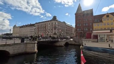 Urban scene in Copenhagen city centre captures Nyhavn canal lined with 17th century buildings, bicycles parked along the waterfront, and people strolling in the afternoon light