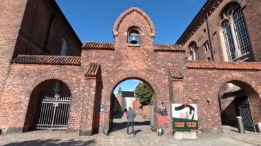 Urban scene in Copenhagen city centre captures Nyhavn canal lined with 17th century buildings, bicycles parked along the waterfront, and people strolling in the afternoon light