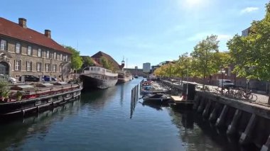 Urban scene in Copenhagen city centre captures Nyhavn canal lined with 17th century buildings, bicycles parked along the waterfront, and people strolling in the afternoon light