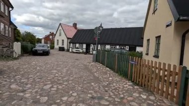 Views of quaint buildings with pitched roofs line the streets of Raa, Sweden's historic fishing village, with calm docks extending into the Oresund waters near Helsingborg.