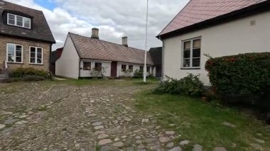 Views of quaint buildings with pitched roofs line the streets of Raa, Sweden's historic fishing village, with calm docks extending into the Oresund waters near Helsingborg.