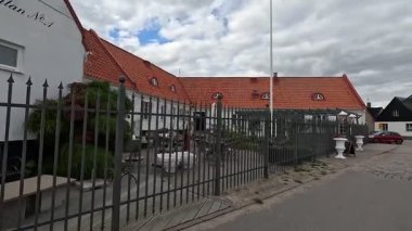 Views of quaint buildings with pitched roofs line the streets of Raa, Sweden's historic fishing village, with calm docks extending into the Oresund waters near Helsingborg.
