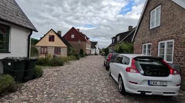 Views of quaint buildings with pitched roofs line the streets of Raa, Sweden's historic fishing village, with calm docks extending into the Oresund waters near Helsingborg.