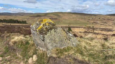 Countryside landscape near Milquhanzie Hill in Perth and Kinross Scotland showing ridge summit with masts, walking paths, and nearby ancient standing stones.