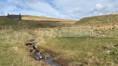 Countryside landscape near Milquhanzie Hill in Perth and Kinross Scotland showing ridge summit with masts, walking paths, and nearby ancient standing stones.
