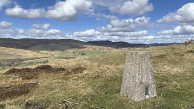 Countryside landscape near Milquhanzie Hill in Perth and Kinross Scotland showing ridge summit with masts, walking paths, and nearby ancient standing stones.
