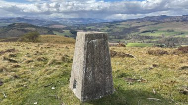 Countryside landscape near Milquhanzie Hill in Perth and Kinross Scotland showing ridge summit with masts, walking paths, and nearby ancient standing stones.