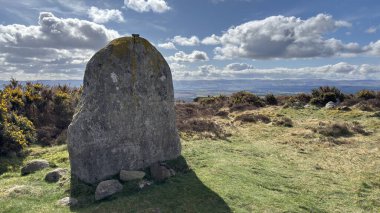 Countryside landscape near Milquhanzie Hill in Perth and Kinross Scotland showing ridge summit with masts, walking paths, and nearby ancient standing stones.