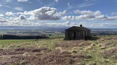 Countryside landscape near Milquhanzie Hill in Perth and Kinross Scotland showing ridge summit with masts, walking paths, and nearby ancient standing stones.