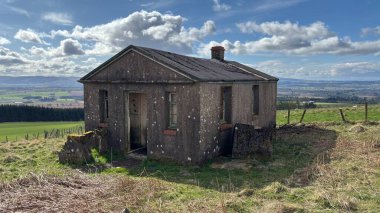 Countryside landscape near Milquhanzie Hill in Perth and Kinross Scotland showing ridge summit with masts, walking paths, and nearby ancient standing stones.
