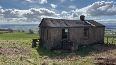 Countryside landscape near Milquhanzie Hill in Perth and Kinross Scotland showing ridge summit with masts, walking paths, and nearby ancient standing stones.