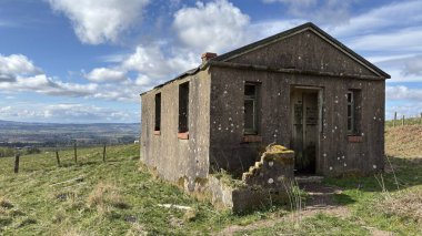 Countryside landscape near Milquhanzie Hill in Perth and Kinross Scotland showing ridge summit with masts, walking paths, and nearby ancient standing stones.